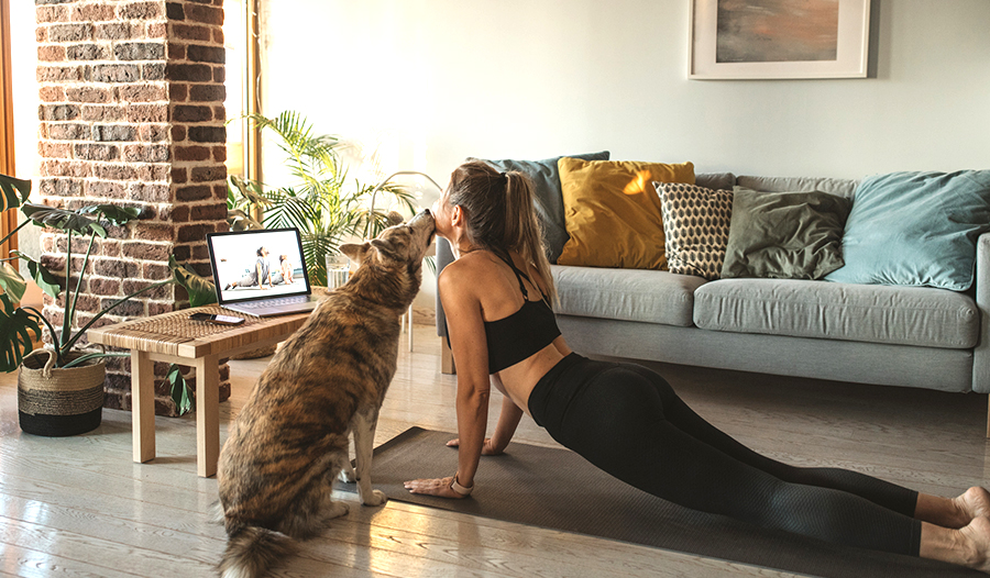 woman practicing self-care by doing yoga at home with her dog