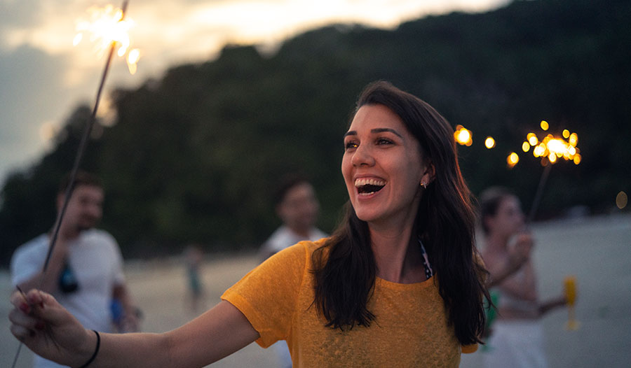 woman celebrating with a sparkler thinking about new year's resolutions