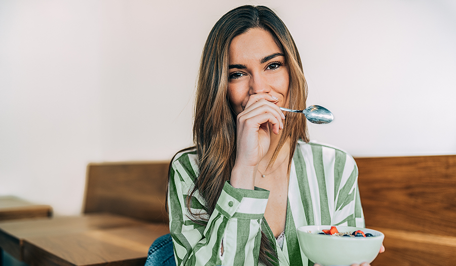 Young woman eating a healthy snack of yogurt and oats