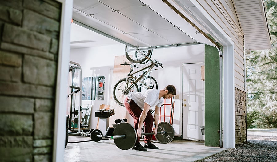 A man working out and lifting weights in his home garage.