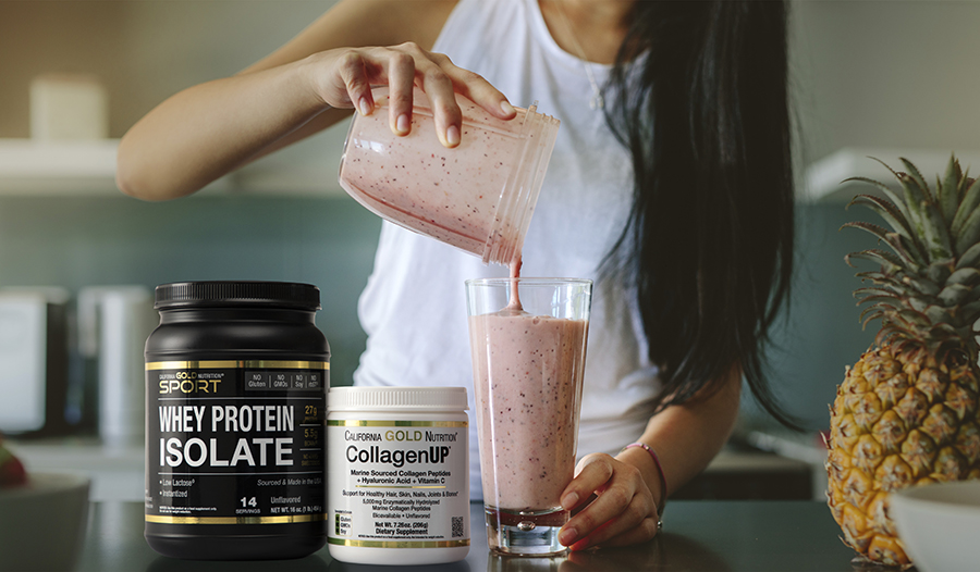 Woman making smoothie in kitchen with whey protein, collagen, and pineapple