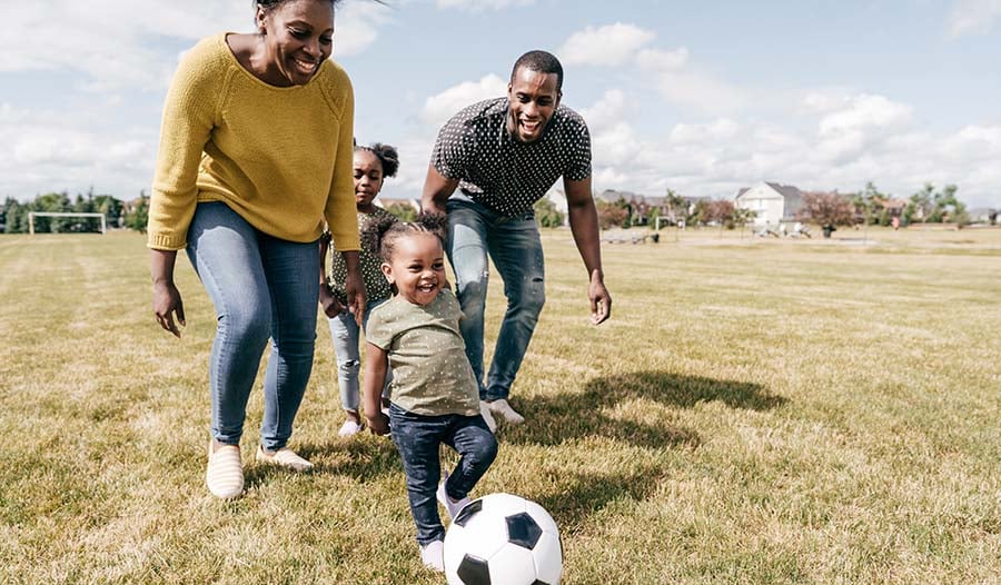 Healthy family playing in the grass with soccer ball