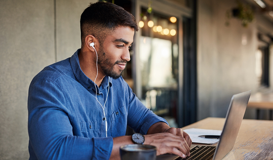 Man with headphones in ears working on laptop