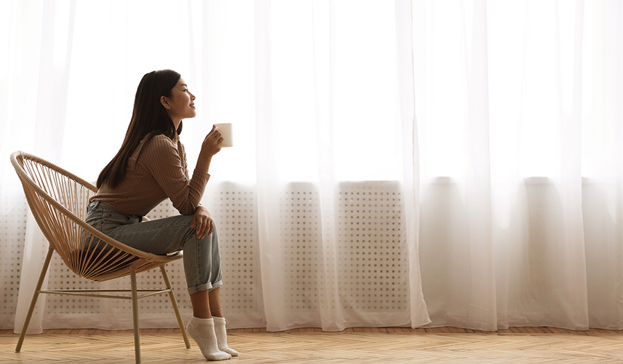 woman practicing self care by sipping coffee by the window