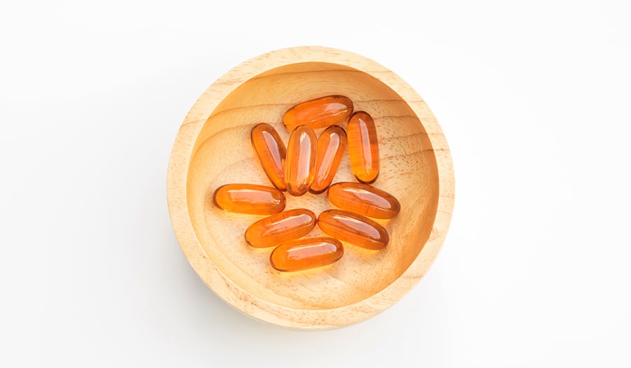 Lecithin gel capsule supplements in wooden tray on white background