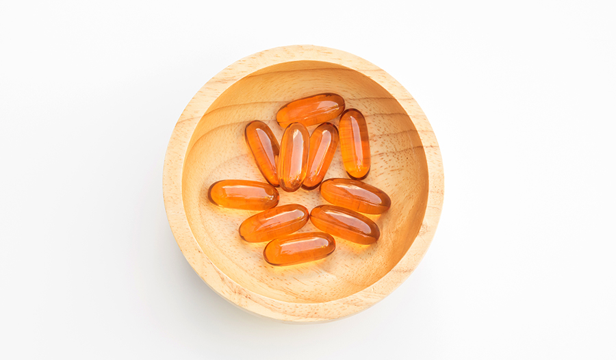 Lecithin gel capsule supplements in wooden tray on white background