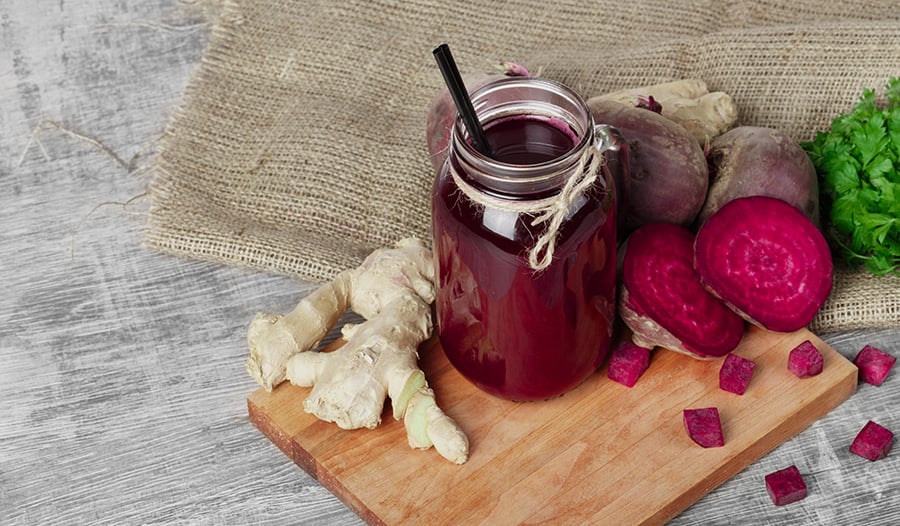 Beet juice in mason jar, ginger, and beets on table