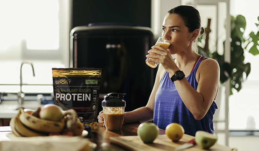 Healthy woman making a smoothie in her kitchen with plant-based protein