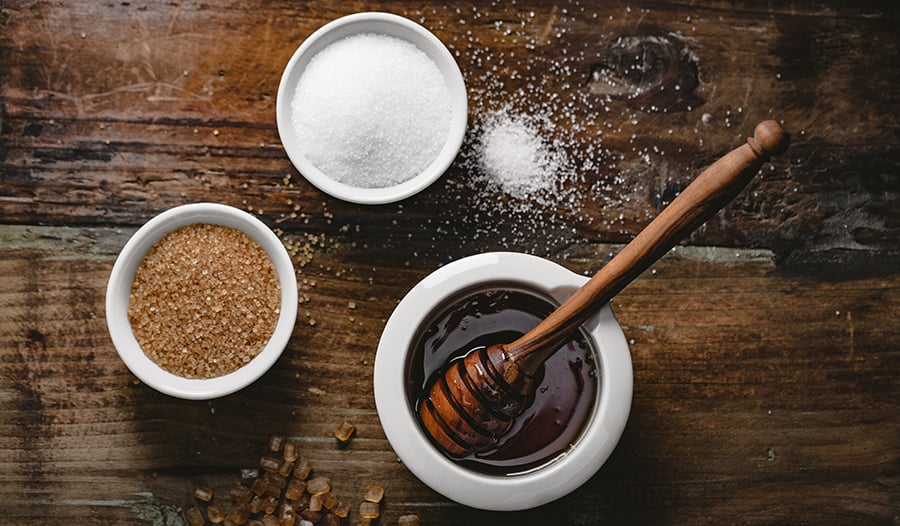 Natural sweetener alternatives like coconut sugar and agave on wooden table