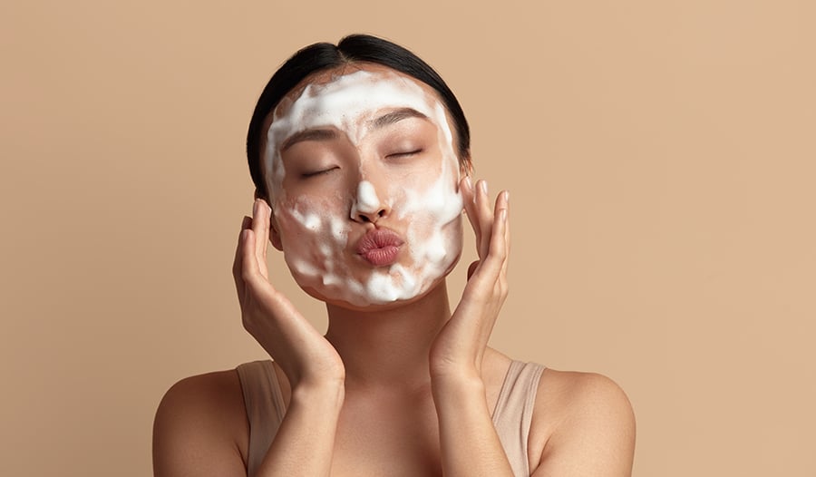 Asian woman washing face with foam cleanser