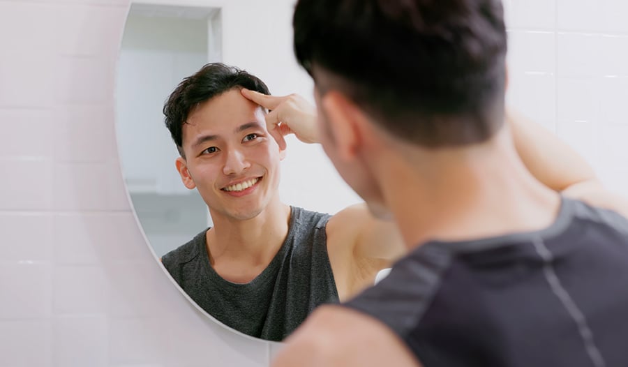 Male looking at hair in bathroom mirror