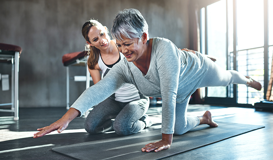 Female trainer working with client on yoga mat 