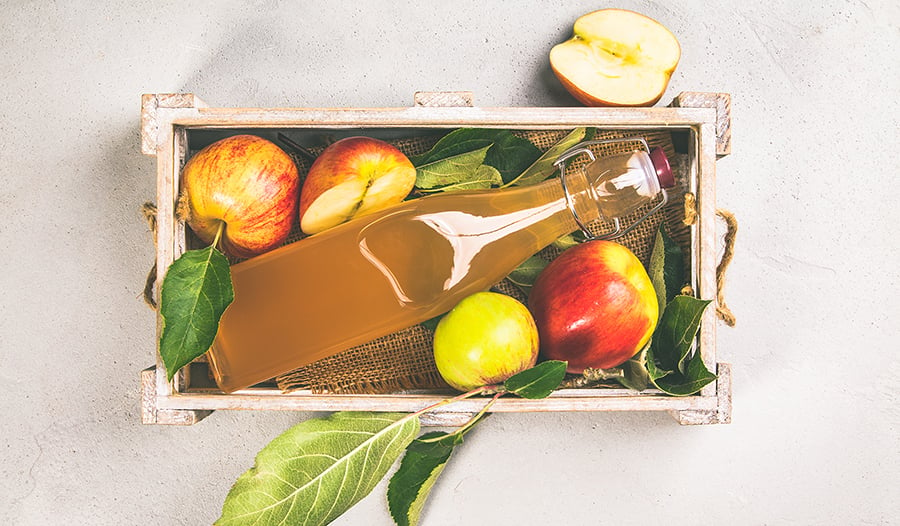 Apple cider vinegar and fresh apples in wooden box