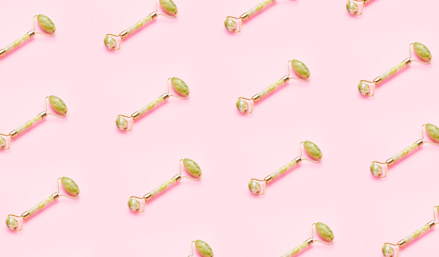 jade facial roller in seamless pattern against pink background