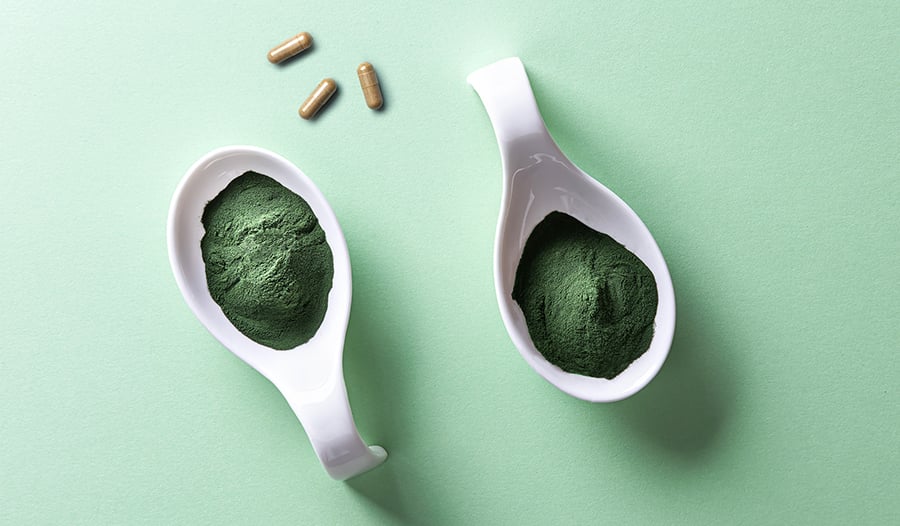 Bladderwrack supplements and spirulina powder on green background