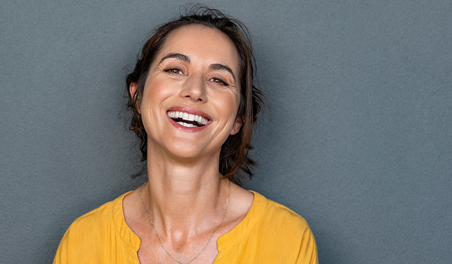 portrait of mature woman in yellow cardigan smiling 