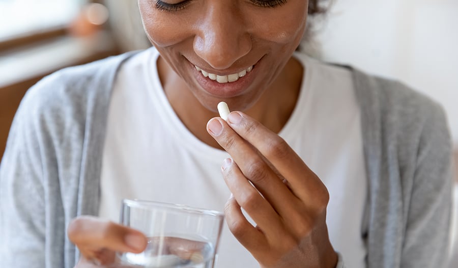 Healthy woman taking a vitamin or supplement with water