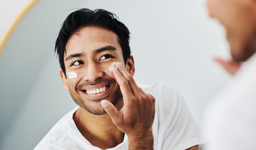 Male applying skincare lotion or product to face
