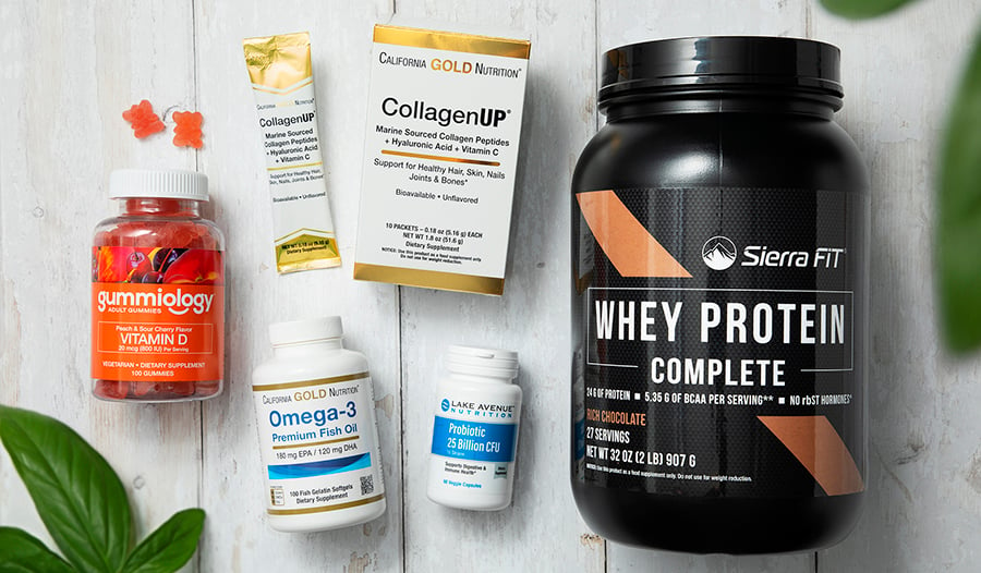 Supplements laid out on white table: vitamin D, collagen, fish oil, probiotics, whey protein