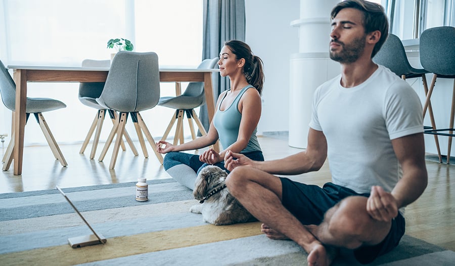 Couple meditating sitting on the floor at home