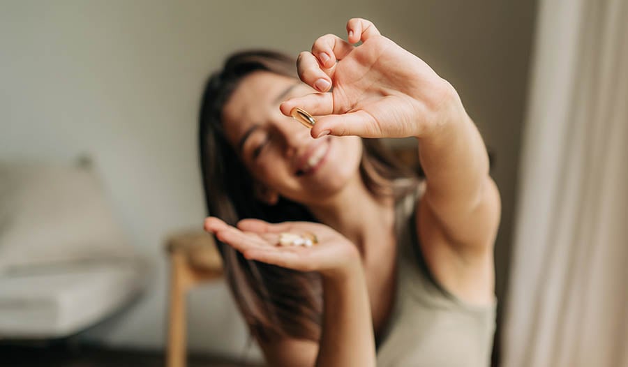Smiling woman holding up fish oil supplement