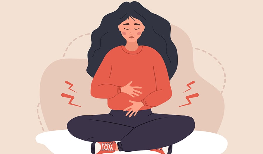 Woman sitting down holding stomach in discomfort
