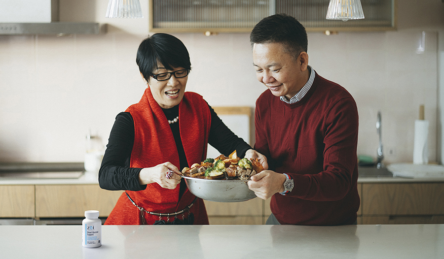 Mature asian couple cooking healthy holiday meal in kitchen with blood sugar supplement on counter