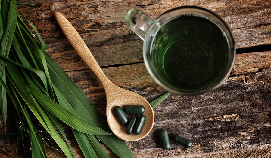 Chlorophyll supplement and green juice on wooden surface