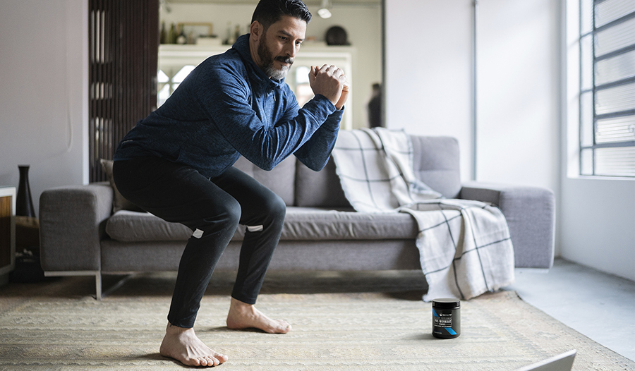 Athletic male working out doing squats at home