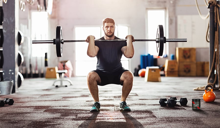 Athletic male doing front squats with barbell in gym