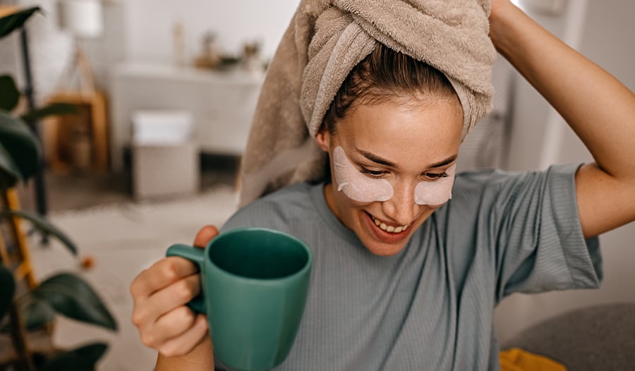 Woman drinking coffee at home doing skin care routine