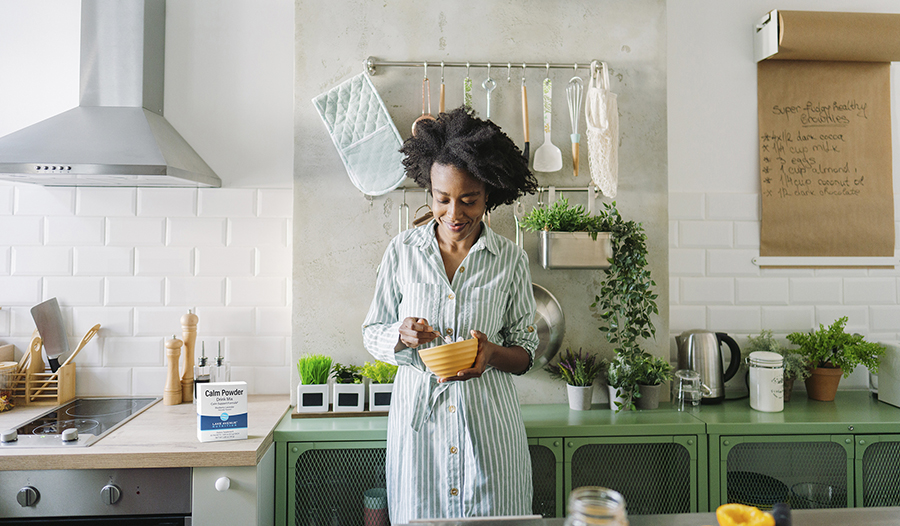 Healthy woman standing by counter in bright kitchen