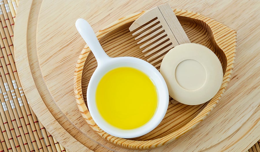 Castor oil in wooden bowl with wooden comb