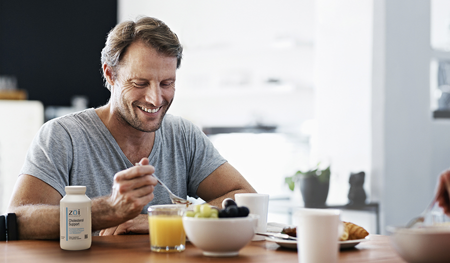 Man eating healthy breakfast with cholesterol support supplement on table