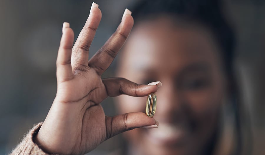 Close up of woman holding a fish oil supplement in her hand