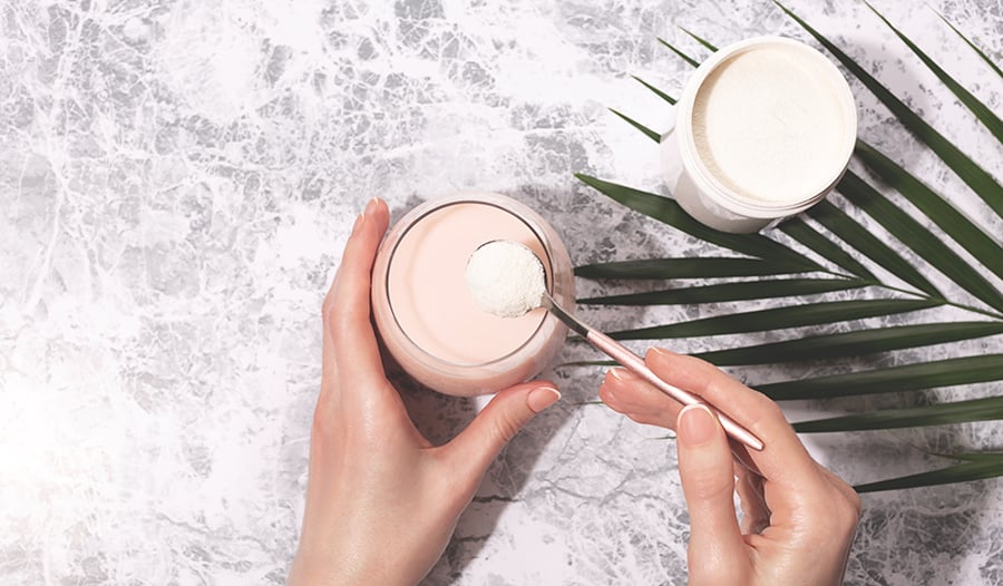 Collagen powder with glass of water and hands holding spoon