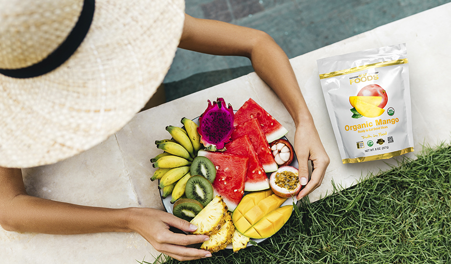 Overhead shot of woman wearing sun hat eating plate of fruit in the pool