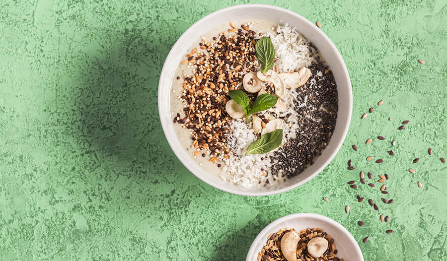 Healthy smoothie bowl with nuts and chia seeds on green table