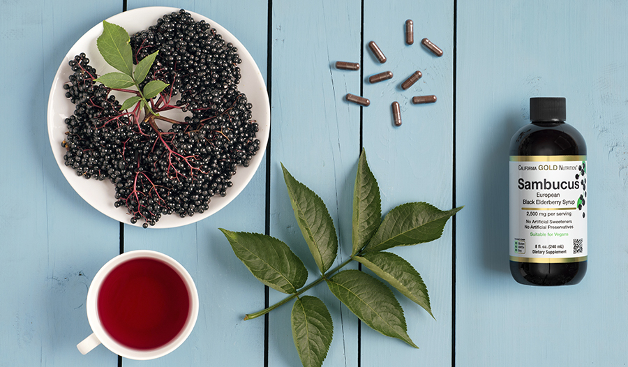 Elderberry fruit, leaves, and supplement bottle on blue table