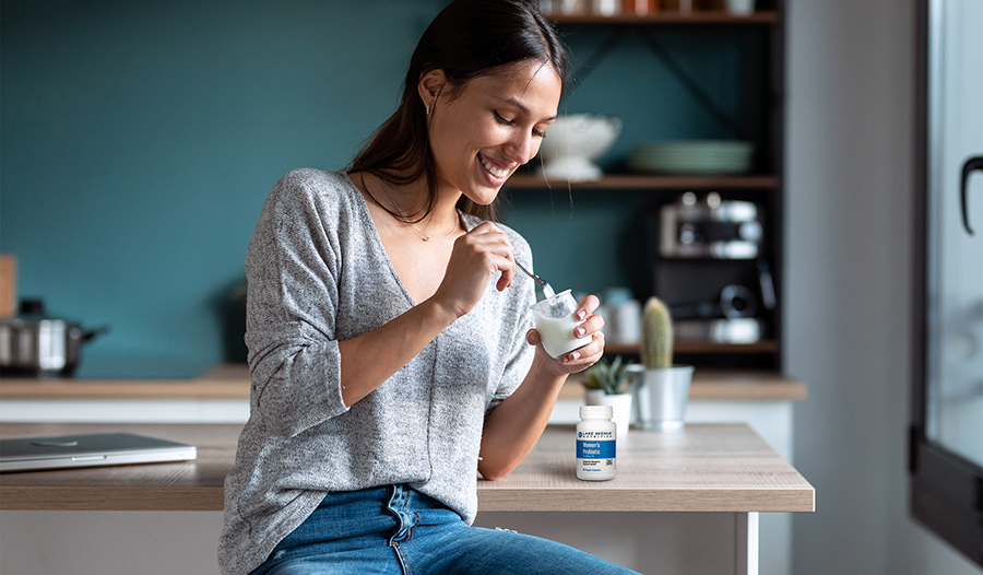 Woman eating yogurt at home in kitchen