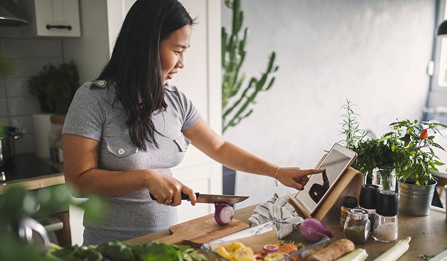 Healthy woman cooking dinner in kitchen chopping vegetables