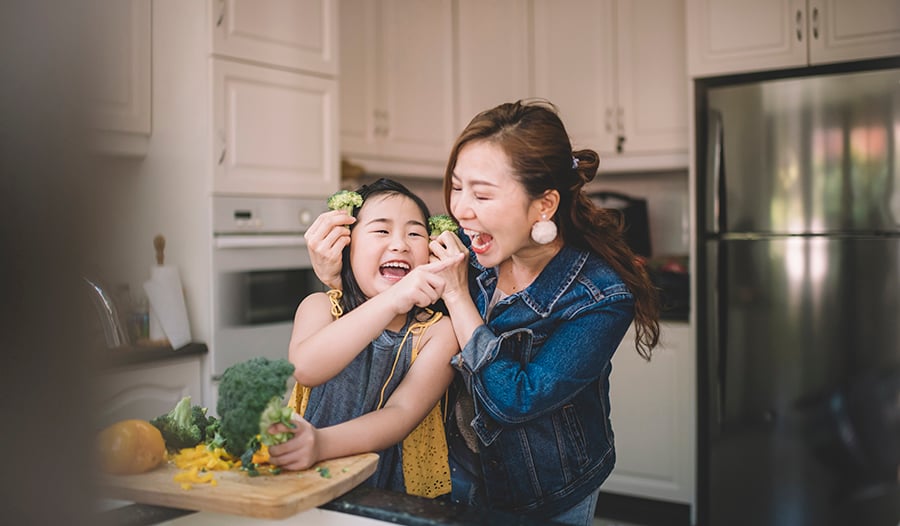 Asian mother and daughter making healthy dinner in kitchen 