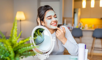 woman applying green tea mask to her face