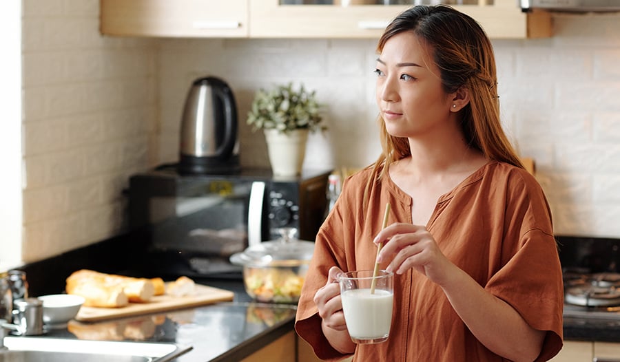 Woman stirring glass of milk in kitchen