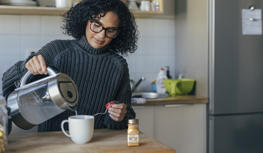 Woman making tea in the kitchen with ginger spice on table