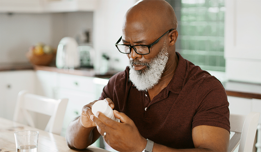 Mature man with glasses examines supplement bottle 