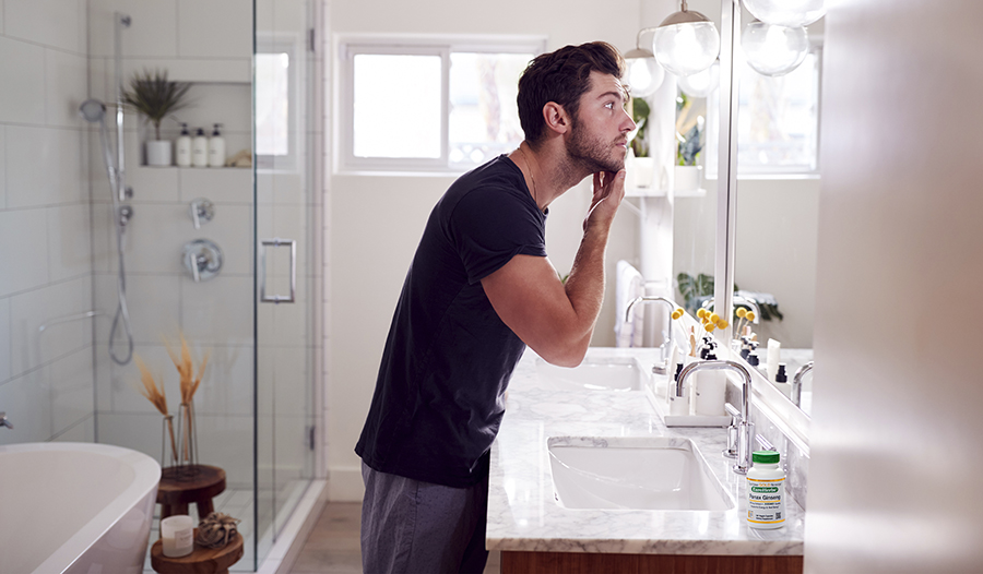 Man standing in bathroom looking in mirror