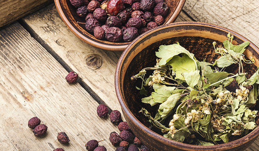 Dried hawthorn berries in bowl on wooden table