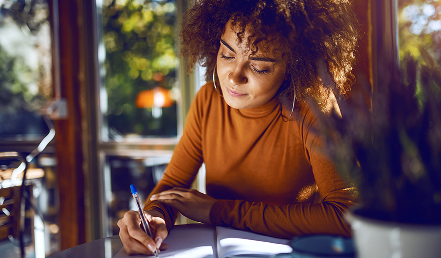 Woman sitting outside at cafe writing in journal