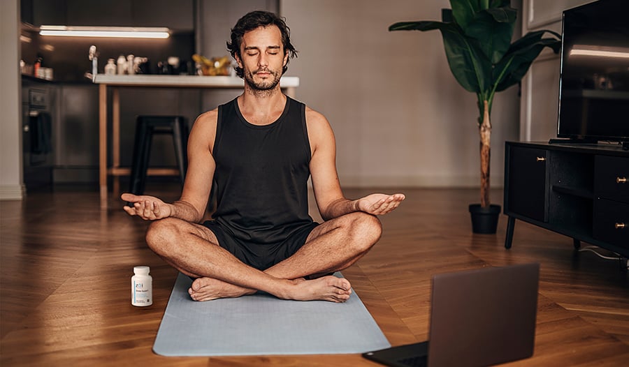 Man meditating on yoga mat at home